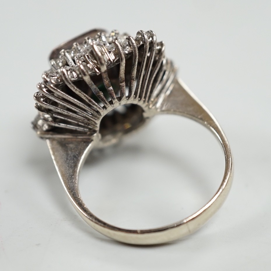 A white metal and single stone emerald set dress ring, bordered with two stepped bands of round and baguette cut diamonds, size K, gross weight 7.6 grams.